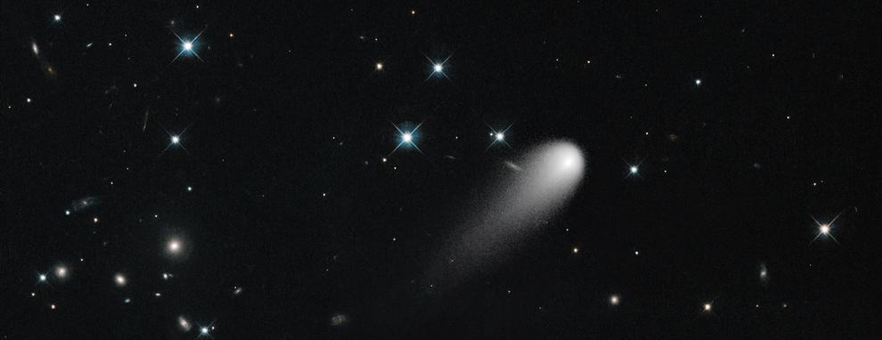 Comet ISON (C/2012 S1) streaks across the darkness of space, with shining stars and distant galaxies in the background