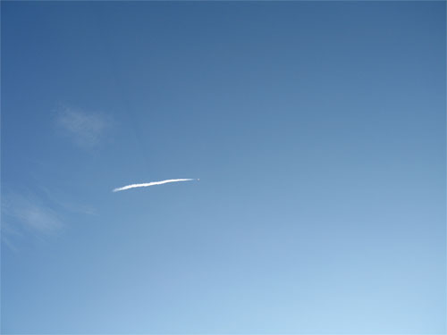 In this image, a vibrantly blue sky serves as the backdrop for a tiny dot of fire with a trail of smoke behind it.  The tiny dot is the Atlas V rocket that launched the Mars Reconnaissance Orbiter and the smoke is the rocket's contrail.